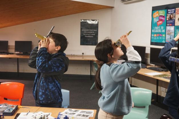 Estudiantes observando luces con un espectroscopio hecho a mano