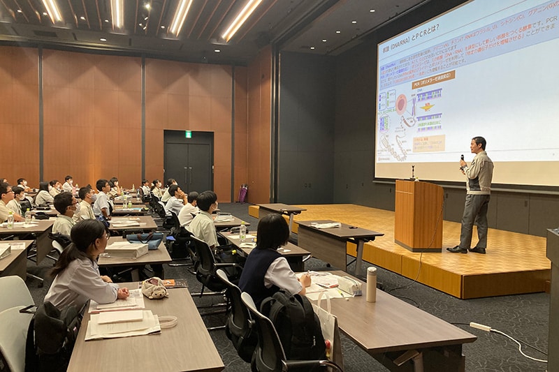Estudiantes escuchando atentamente un discurso sobre el trabajo en equipo durante el desarrollo del sistema de pruebas PCR