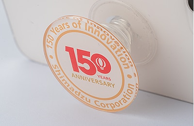 A smartphone stand and mouse pad featuring the anniversary logo (produced by SSL)