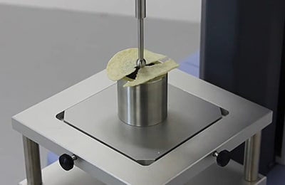 Products such as universal testing machines were introduced as examples of Shimadzu’s technologies. The photo shows a demonstration of measuring the hardness of snack foods.