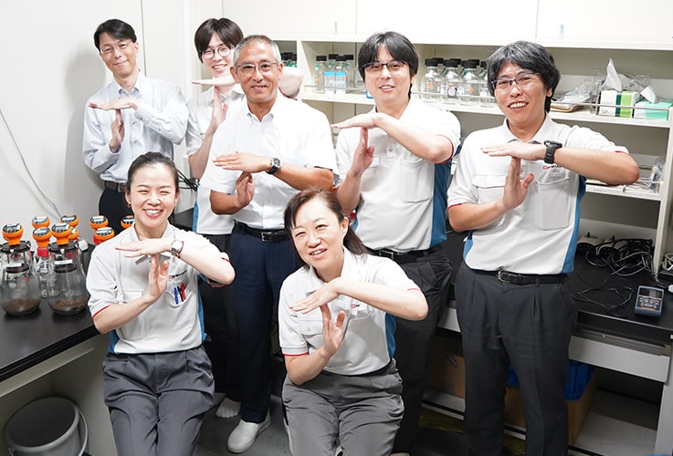 Makoto Yasojima, the third from the left in the back row, photographed with members of the research team at the Shimadzu Techno-Research laboratory
