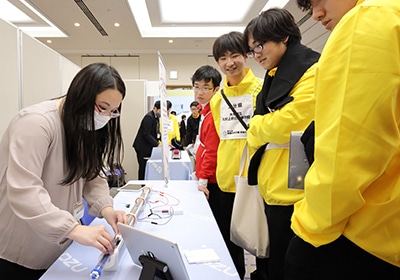 A Shimadzu Rika employee demonstrating the “Magnet Train Passing Through a Coil” mechanics experiment kit at the corporate exhibition booth