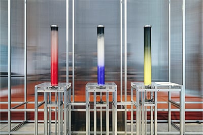 “Particle Settling”: Pressing the button on the stand sends two powdered mineral pigments up through a cylinder, where they mix. As time passes, the particles descend at different speeds because of differences in weight, forming naturally layered color gradients.