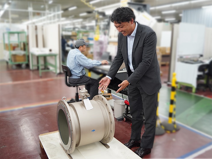 Yasue explaining an electromagnetic flow meter used to measure the volume of water flowing through pipes