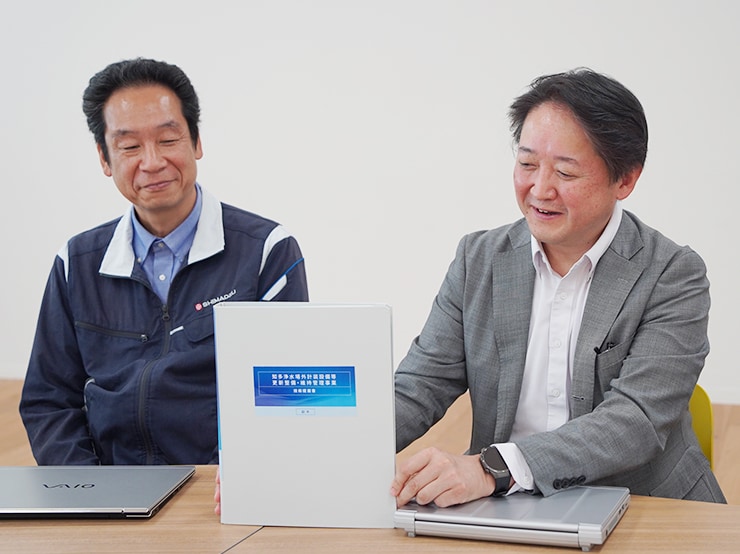 Onoue (right) and Tanaka holding the technical proposal document