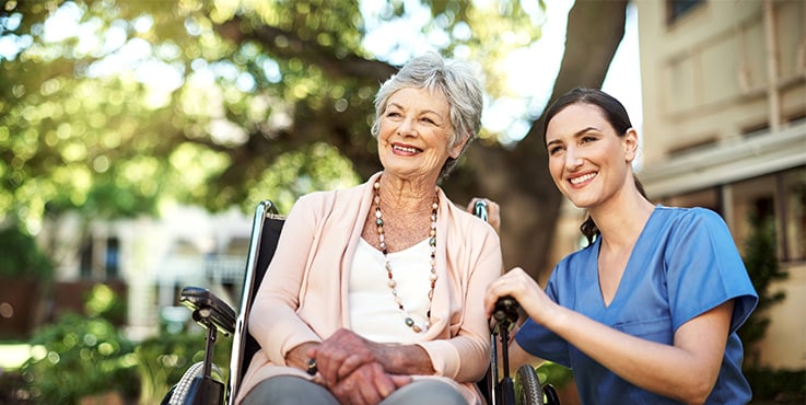 Two women smiling in the gentle sunlight filtering through the trees