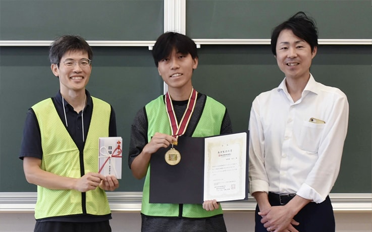 A Shimadzu Rika Corporation microscope was presented as the Shimadzu Prize. From left: Organizing Committee Chair Professor Koichi Kobayashi of Osaka Metropolitan University, award recipient Takamadate, and Shimadzu’s Kitamura